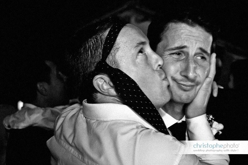 Groom making a funny face while being hugged and kissed by his crazy bestman. Wedding Photojournalism in Italy.