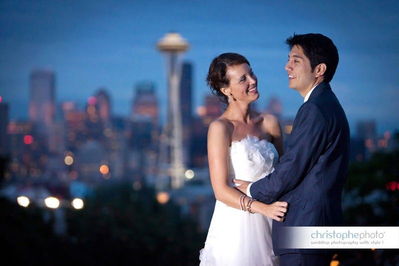 Bride and groom posing at twilight with the Seattle skyline behind them. Directed by Wedding Photographer Seattle