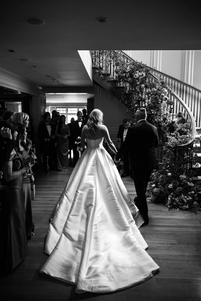 Dramatic black and white photograph of bride entering the ceremony in a private home.